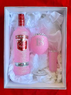 a pink bottle and two wine glasses in a box