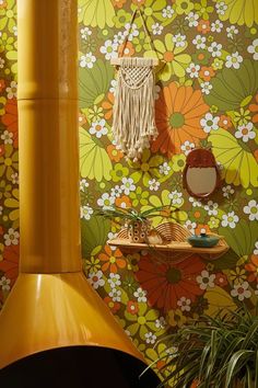 a yellow stove top oven sitting next to a wall covered in colorful floral wallpaper