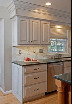 a kitchen with white cabinets and black counter tops