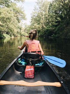 a woman is paddling her canoe down the river