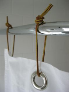 an ironing board hanging from a hook on a white curtain with a knot around it