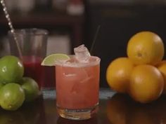 a close up of a drink on a table with lemons and limes in the background