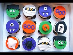 cupcakes decorated to look like halloween characters are in a white box with black and orange frosting