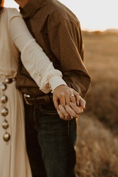 a man and woman holding hands in an open field