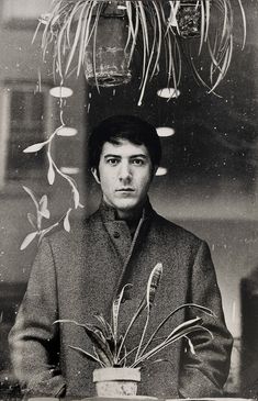 an old black and white photo of a man holding a potted plant in front of him