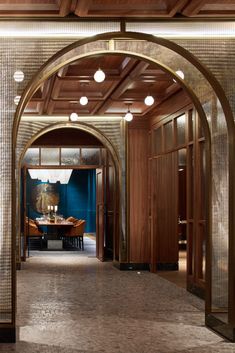 an archway leads into a dining room with blue walls and wood paneled ceilinging