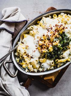 a bowl filled with macaroni and cheese on top of a wooden cutting board