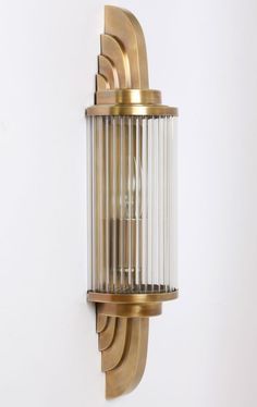 a wall mounted light on the side of a white wall with gold trimmings