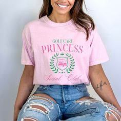 Elevate your golf attire with the charming "Golf Cart Princess Social Club" tshirt. Designed with the stylish golf enthusiast in mind, this Comfort Colors shirt is the perfect gift for the golf wife or golf girl in your life. Featuring an elegant and playful design, this apparel exudes both comfort and sophistication, making it suitable for a day on the course or a casual outing at the country club. This is a standard unisex size Comfort Colors Tee. For an oversized tee, please size up. If you a Cute Golf Shirts Women, Pink Short Sleeve Tops For Golf, Preppy Cotton Tops For Golf, Graphic Tee Tops For Golf, Graphic Tee Golf Tops With Short Sleeves, Graphic Tee Tops For Golf With Short Sleeves, Golf Wife, Club Tshirt, Golf Girl