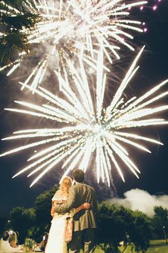 a bride and groom standing in front of fireworks