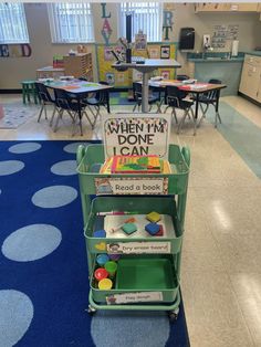 there is a green cart with books on it in the middle of a school room