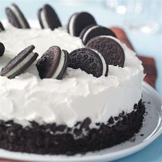 an oreo cookie cake with white frosting and cookies on top is sitting on a plate