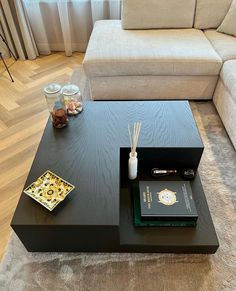 a living room with a couch, coffee table and books on the floor in front of it