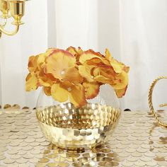 a vase filled with yellow flowers sitting on top of a table covered in gold circles