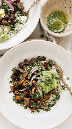 two white plates filled with food on top of a table next to bowls and utensils