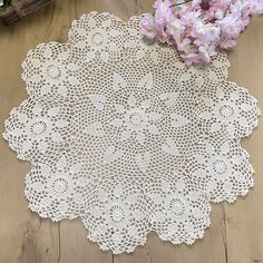 a white doily sitting on top of a wooden table next to flowers and a basket