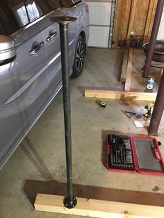 a car is parked in a garage with tools on the floor next to it,