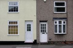 two houses side by side with white doors and windows on either side of the street