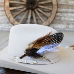 This handmade arrangement of feathers is the perfect way to set your hat apart from the rest. Simply tuck into the band of any hat. Made with a mix of Guinea and rooster feathers. Approximately 7.5 inches long, sizes may vary due to being made with natural materials. Includes: 1 Handmade Arrangement of Feathers. How to use: Tuck into the hat band of any hat. Approx. 7.5 inches - sizes may vary slightly *Hat not included.* Feathered Short Brim Hat Bands For Western-themed Events, Feathered Hat Bands For Western-themed Events, Feathered Flat Brim Hat Bands For Rodeo, Feathered Felt Hat With Flat Brim For Western-themed Events, Feathered Flat Brim Felt Hat For Western-themed Events, Western Style Brimmed Top Hat With Feathers, Western Felt Hat With Feathers For Kentucky Derby, Vintage Felt Hat With Feathers For Western-themed Events, Western-themed Felt Hat With Feathers And Flat Brim