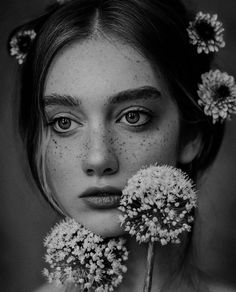 a woman with freckles on her face and flowers in front of her face