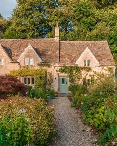 a stone house surrounded by greenery and flowers on a sunny day in the countryside