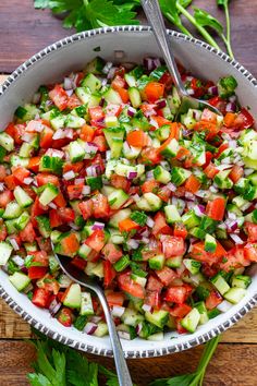 a bowl filled with cucumber and tomato salad on top of a wooden table