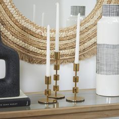 some candles are sitting on a shelf next to a vase and other items in front of a mirror