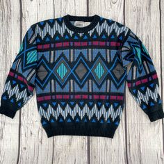 "1990s Vintage Gabrielle brand pullover sweater has major Coogi vibes. Geometric diamond and zig-zag pattern with real black leather detailing across the front. This well-made crewneck has multiple knitted textures, ribbed cuffs and waist. Black with vibrant teal, blue, red, white, and a little bit of tan.  Very good vintage condition. Marked as a Size Medium.  (Vintage sizes may vary from today's modern sizing, so please refer to measurements to ensure correct fit.) Measurements are taken with Casual Geometric Pattern Sweater For Winter, Winter Crew Neck Sweater With Geometric Pattern, Winter Geometric Pattern Crew Neck Sweater, Retro Long Sleeve Argyle Sweater, Black Argyle Pattern Crew Neck Sweater, Black Argyle Crew Neck Sweater, 90s Style Black Winter Sweater, Vintage Argyle Sweater For Fall, Retro Black Sweater With Fair Isle Pattern