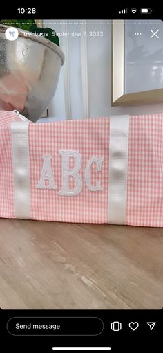 a pink and white checkered bag sitting on top of a wooden table next to a metal bowl