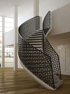 a spiral staircase in the middle of a room with wooden floors and white walls, along with large windows