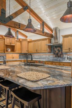 a large kitchen with wooden cabinets and granite counter tops, an island in between two bar stools