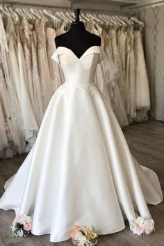 a white wedding dress on display in a bridal room with other dresses and flowers