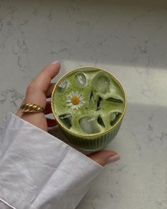 a hand holding a cup filled with green liquid