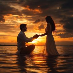 a man kneeling down next to a woman in the water with their hands on each other