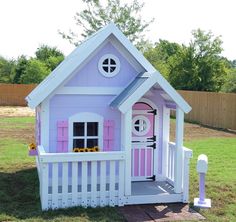 a pink and white doll house with flowers on the front door, porch and fence