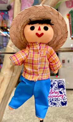 a doll with a straw hat and blue pants holding a shopping bag in its hand