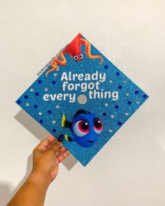 someone holding up a blue graduation cap with an image of finding nemo on it