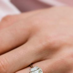 a close up of a person's hand with a diamond ring on their finger