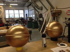 two large metal balls sitting on top of a wooden table in a room with lots of tools