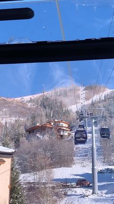 a ski lift going up the side of a snow covered mountain next to a building