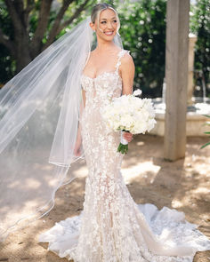 a woman in a wedding dress with a veil on her head and flowers in her bouquet