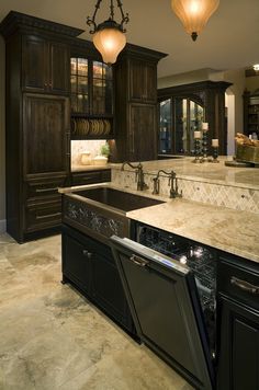 a kitchen with marble counter tops and black cabinets, an island sink and dishwasher