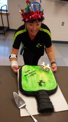 a woman wearing a birthday hat cutting a cake