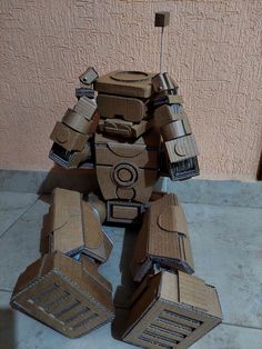 a robot made out of cardboard sitting on the ground