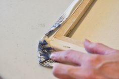 a person holding something in their hand near a box with an open lid and paper on it