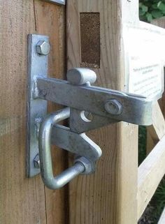 a close up of a metal latch on a wooden door with a sign in the background