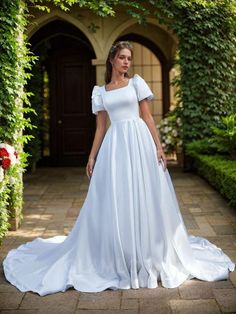 a woman wearing a white wedding dress standing in front of an archway with greenery