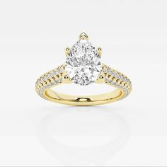 a yellow gold engagement ring with an oval cut diamond in the center and pave set shoulders