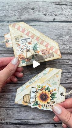 two handmade paper airplanes are being held by someone's hands on a wooden table