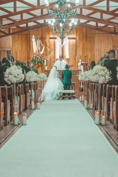 a bride and groom standing at the end of a church aisle with candles in front of them